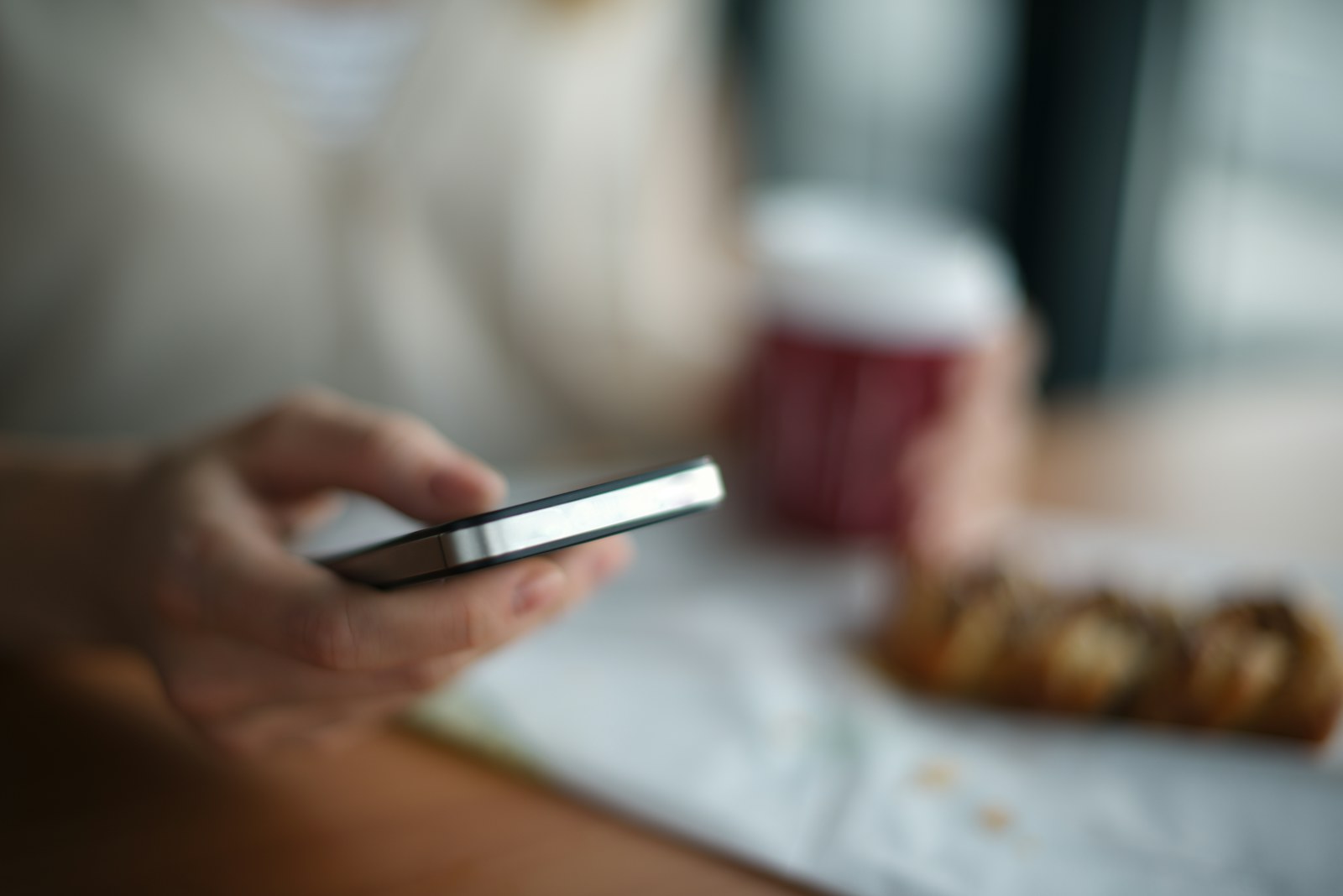 Gast met een telefoon aan een cafétafel